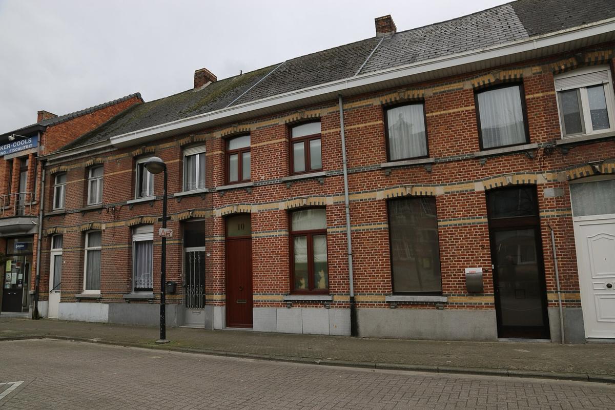 Een rij bakstenen dorpswoningen met houten ramen en deuren in Koningshooikt